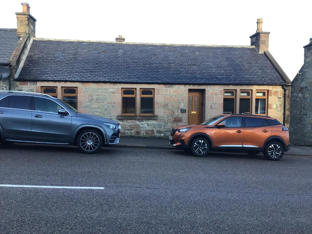 twee auto's geparkeerd voor een huis bij Lyngarrie in Dufftown