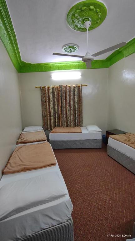 um quarto com 3 camas e um tecto verde em DAR MOHAMMED HOTEL دار محمد فندق em Sīdī Ḩamzah