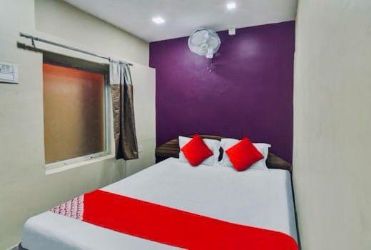 a bedroom with a bed with red and white pillows at HOTEL AIRPORT HEAVEN in kolkata