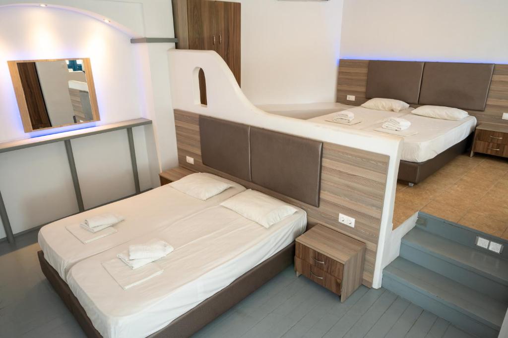 two beds in a small room with a mirror at Fanari Art in Ios Chora