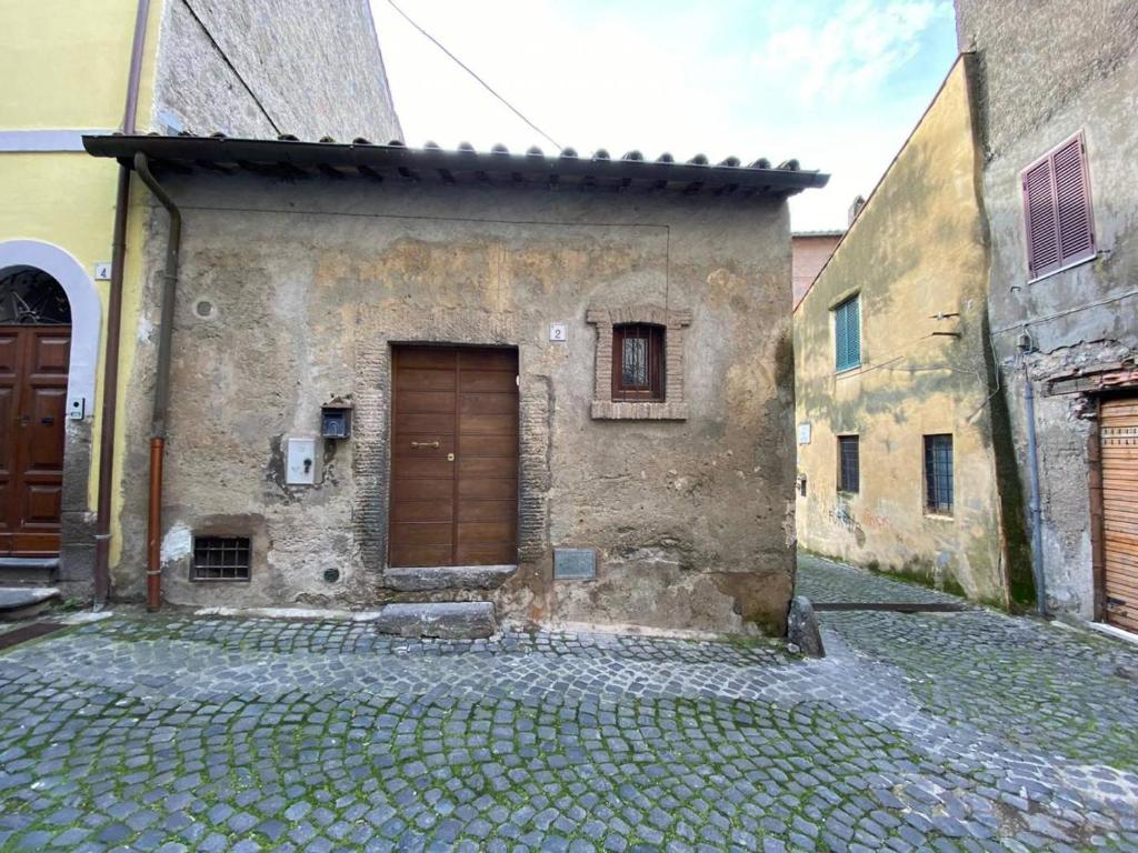 a stone building with a wooden door on a street at La Fenice 3 0 in Bracciano