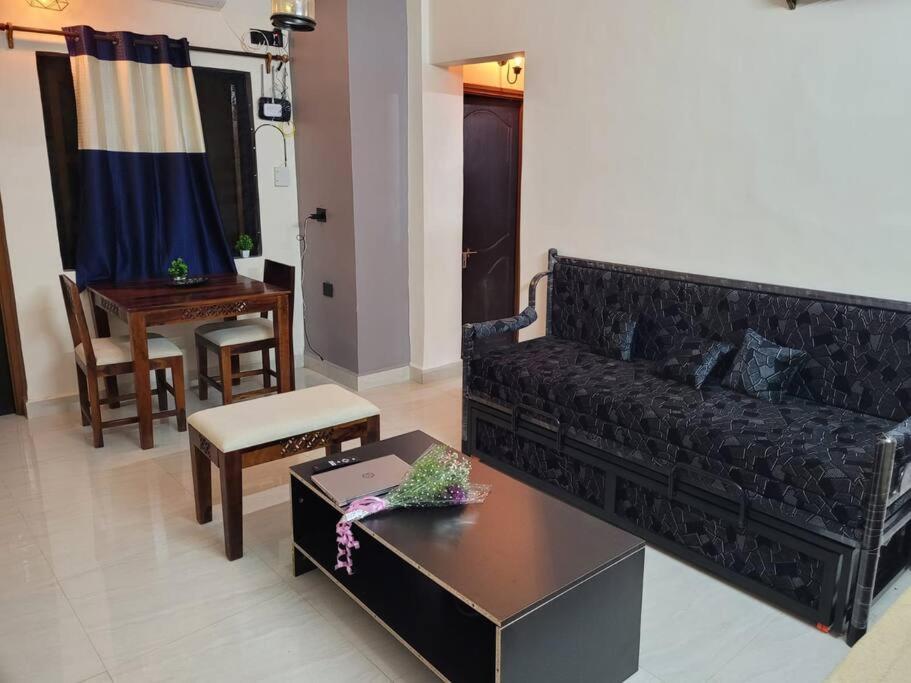 - un salon avec un canapé noir et une table dans l'établissement Comfortable 1BHK Resort Aptmt with Pool at Candolim for 4 ppl, à Goa