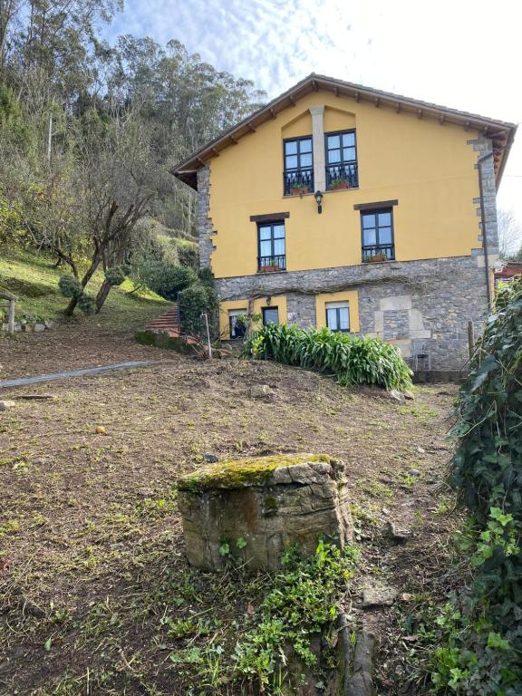 a yellow house with windows on top of a yard at LOS CARBAYINOS in Villaviciosa
