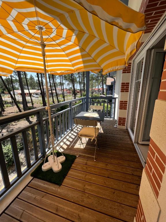 - un balcon avec un parasol, une table et des chaises dans l'établissement Appartement calme et cosy à Andernos-Les-Bains, à Andernos-les-Bains