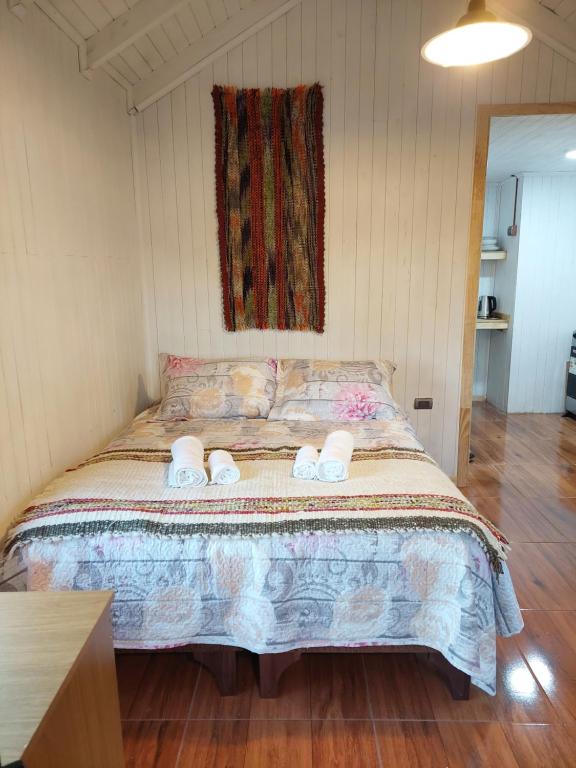 1 dormitorio con 1 cama con 2 zapatillas en Cabaña Loft Curaco de Vélez, en Curaco de Velez