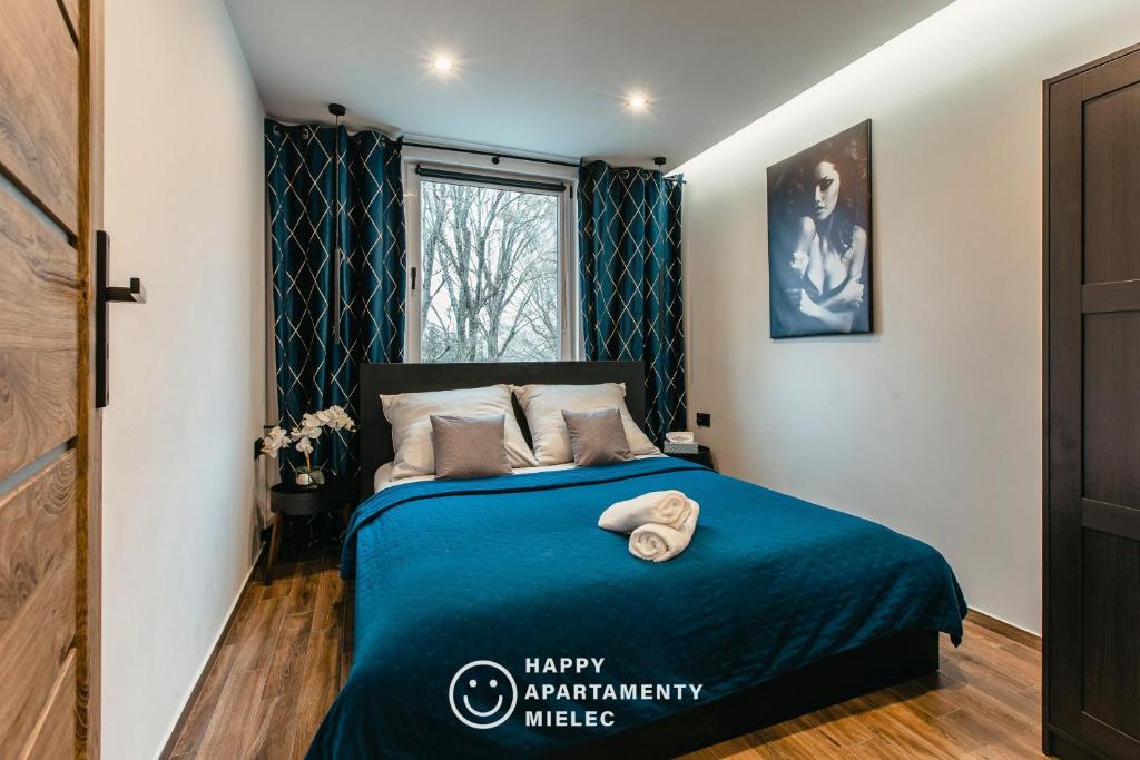 a bedroom with a bed with a blue blanket at Happy Time - Happy Apartamenty Mielec in Mielec