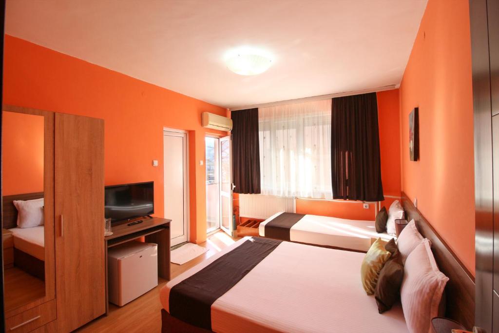 ズラトグラッドにあるFamily Hotel Floraのベッドとテレビが備わるホテルルームです。
