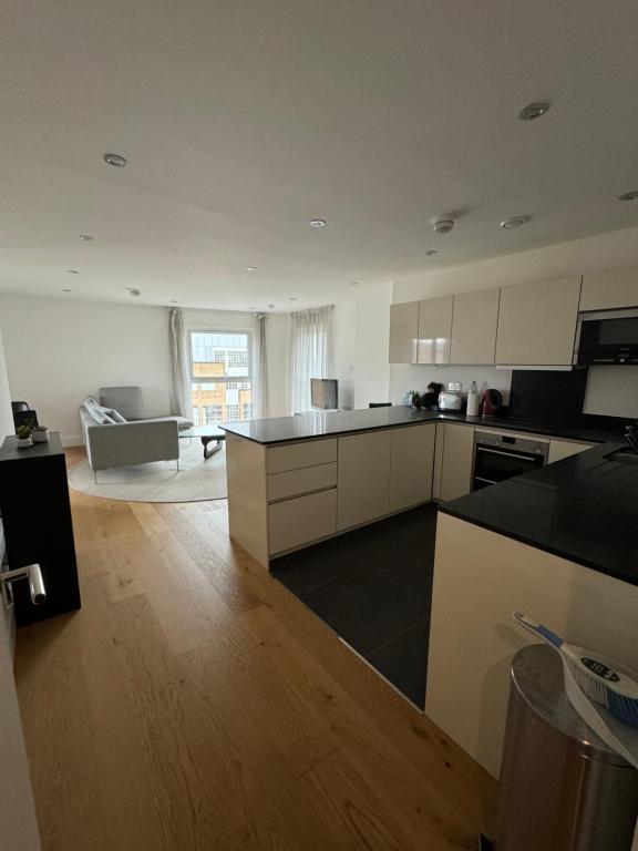 a kitchen with white cabinets and a living room at Entire Kingston Two bedroom Apartment Town centre & River view, 32 minutes to London Waterloo Station in London