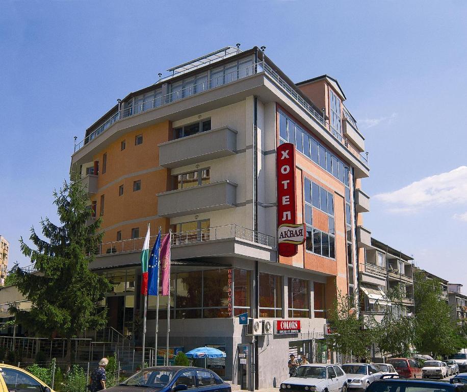 un edificio alto con coches estacionados frente a él en Hotel Akvaya, en Veliko Tŭrnovo