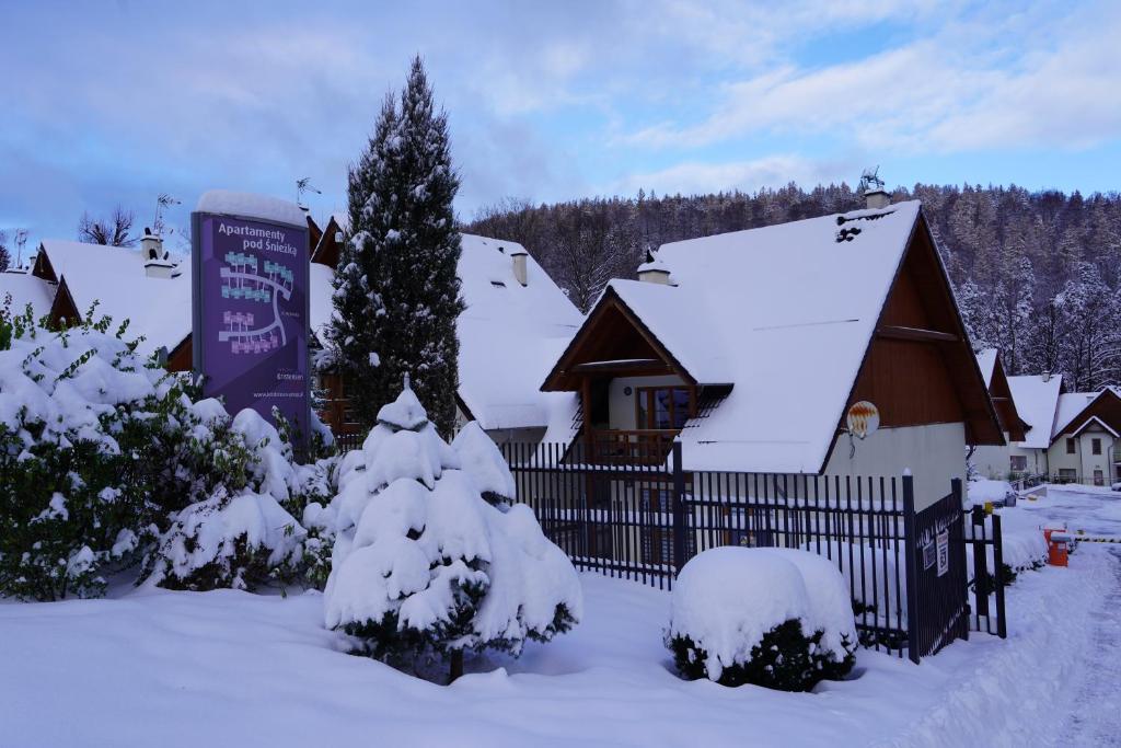 een huis bedekt met sneeuw met een hek en een kerstboom bij IKS holiday in Karpacz