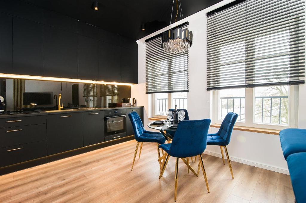 a kitchen with a dining room table and blue chairs at Black Pearl Apartment starówka in Elblag
