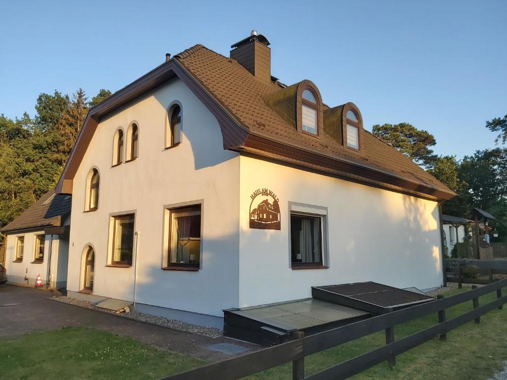 een wit huis met een bruin dak bij Haus am Wald - Haus Nils und Haus Nele in Bark