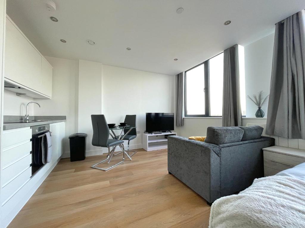 a living room with a couch and a table and a kitchen at Amazing Views of the City in Manchester