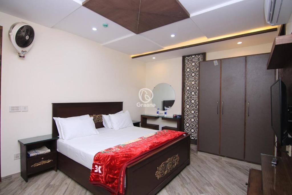 1 dormitorio con 1 cama grande con manta roja en Multazam Heights, DHA Phase 8 en Lahore
