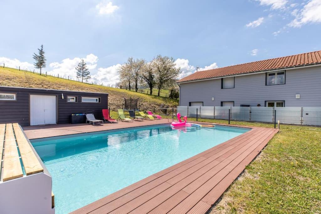 una piscina con terraza de madera junto a una casa en Maison Piscine Zénith d'auvergne Clermont Sud, en La Roche-Blanche