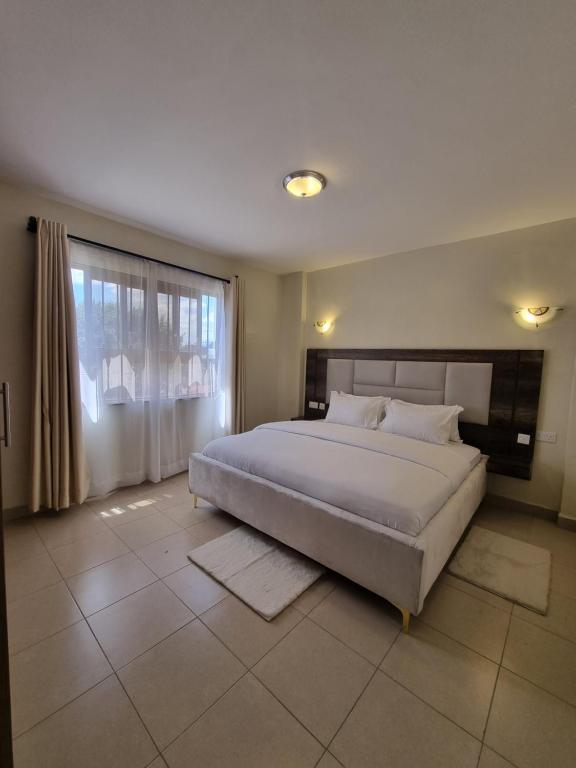 ein Schlafzimmer mit einem großen Bett und einem großen Fenster in der Unterkunft SRS (Swadakta Royal Suites) in Nakuru