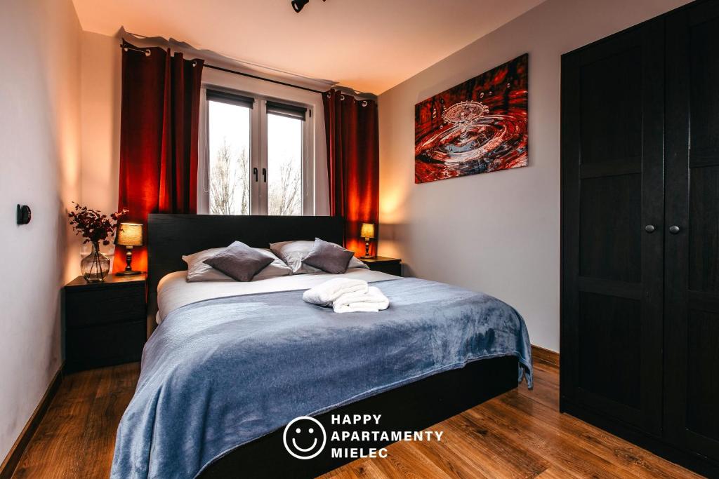 een slaapkamer met een bed met een blauwe deken bij Happy Stay - Happy Apartamenty Mielec in Mielec