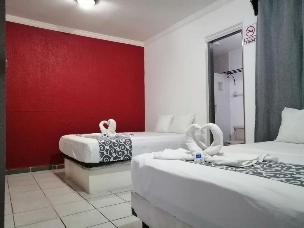 Habitación de hotel con 2 camas y pared roja en Hotel & Suites Bausan en Boca del Río