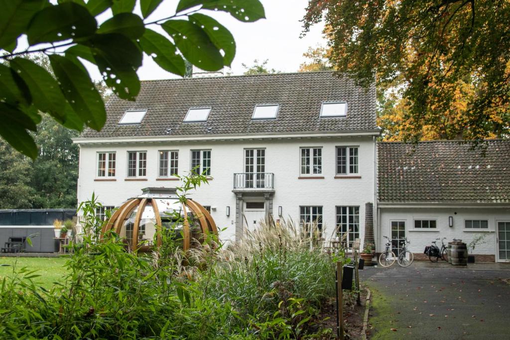 Uma casa branca com uma roda à frente. em Hof Ter Beuke em Bruges