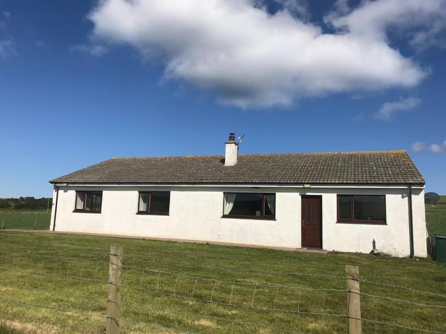 een wit huis met een hek in een veld bij Inishroel Cottage in Campbeltown