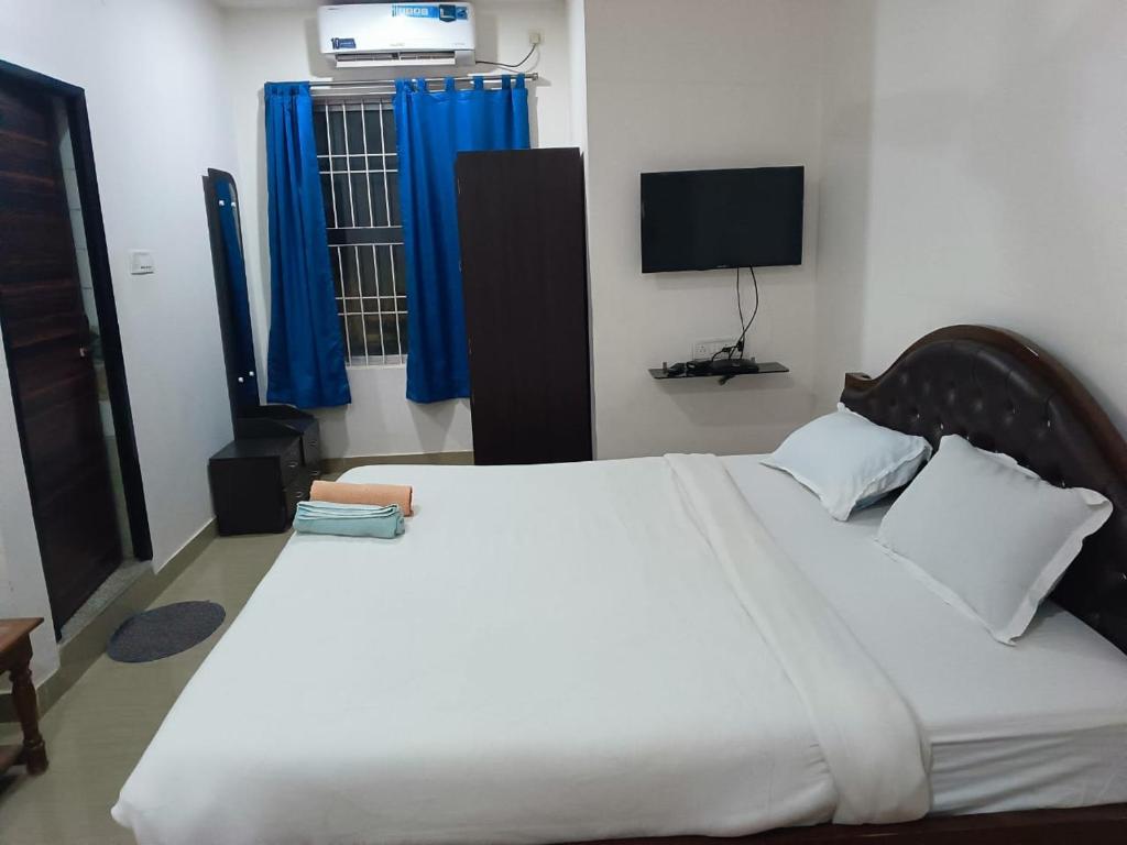 a bedroom with a large white bed with blue curtains at HOTEL MOON-LITE in Guwahati