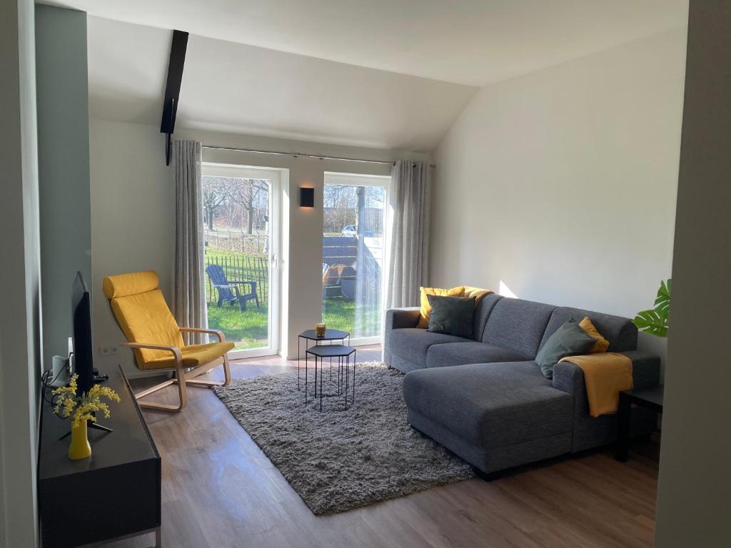 un soggiorno con divano e sedia di Appartementen Chaamse Bossen met tuin a Chaam