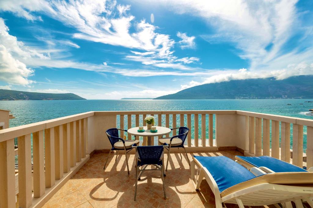 a balcony with a table and chairs and the ocean at Palma Apartments in Herceg-Novi