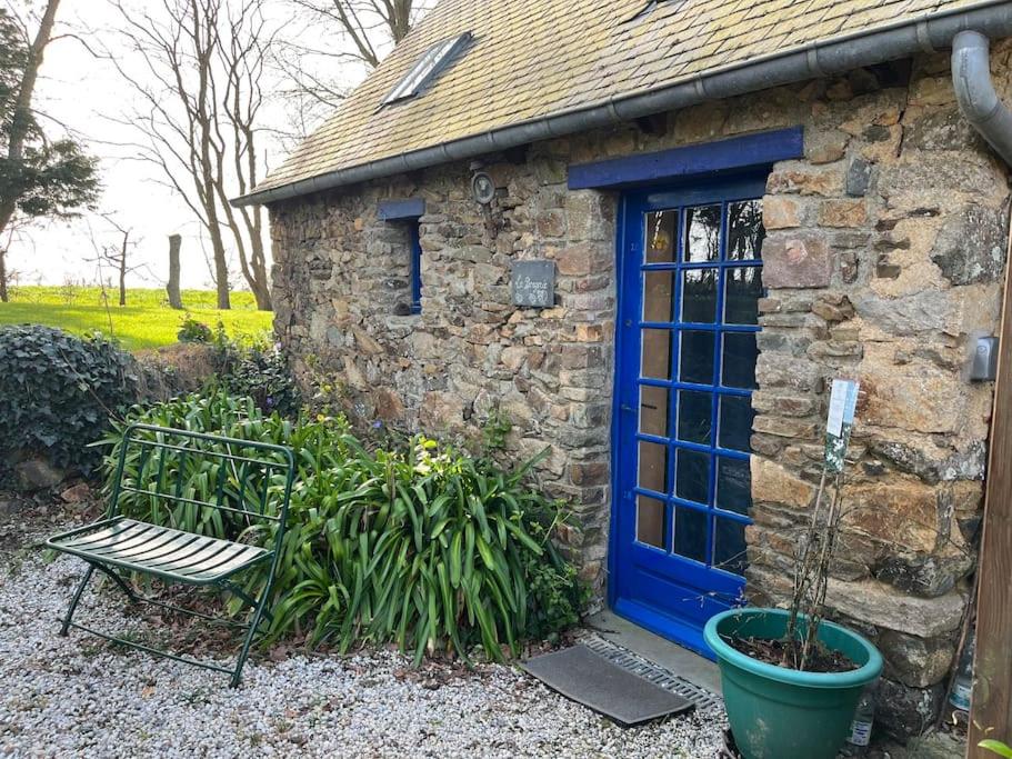 un edificio in pietra con una porta blu e una panchina di La Bergerie a Plouha