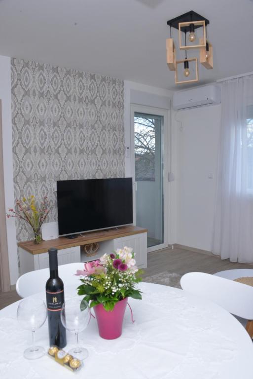 uma sala de estar com uma mesa com copos de vinho e uma televisão em Bella em Sremska Mitrovica