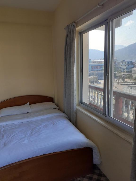 um quarto com uma cama e uma janela grande em Hotel Vibe by Solitary em Pokhara