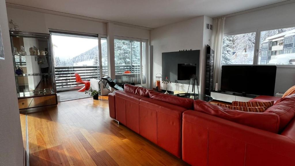 a living room with red couches and a television at Grüenipark Davos in Davos