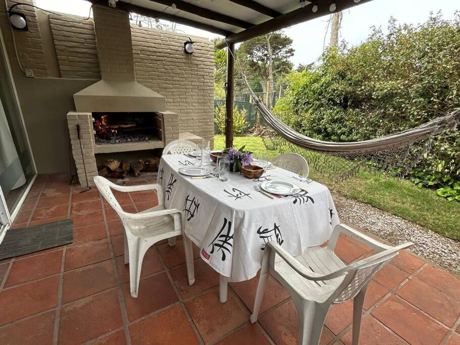une table et des chaises sur une terrasse avec une cheminée dans l'établissement Aurelia. Dúplex en complejo cerrado en San Rafael, à Punta del Este