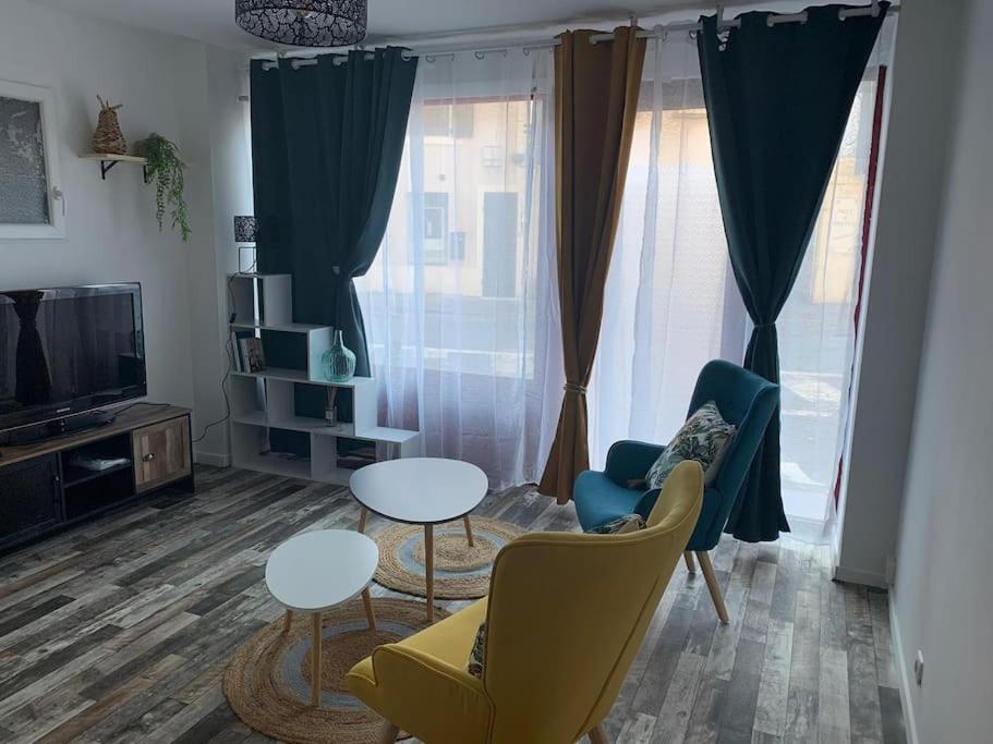 salon z krzesłami, stołami i telewizorem w obiekcie Appartement avec cours w mieście Gien