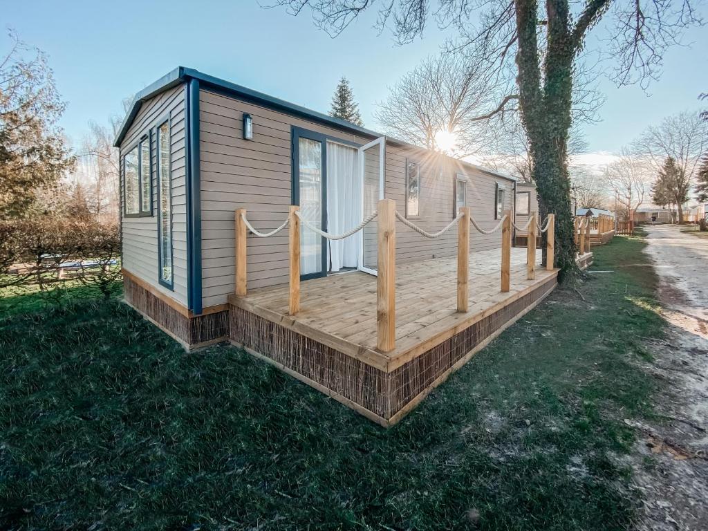 a tiny house with a wooden deck in the yard at Soleil Levant in Berdorf