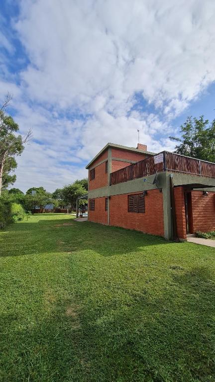 a red brick building with a grass field in front of it at Cabaña LA JUANA in Villa Anizacate