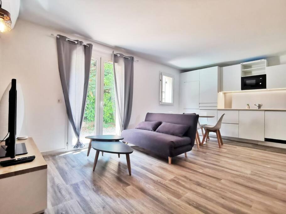 un salon avec un canapé et une table dans l'établissement Les quatre loges - joli t2 jardinet et parking *3, à Aix-en-Provence
