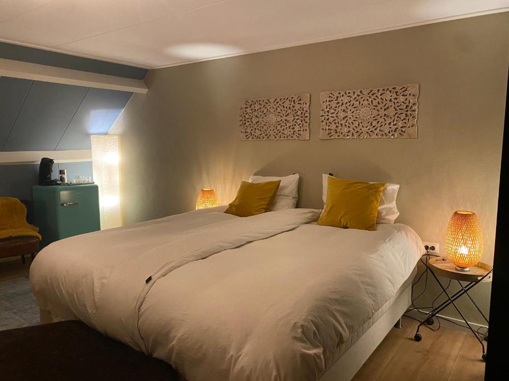 - une chambre avec un grand lit blanc et des oreillers jaunes dans l'établissement Bed and breakfast Carma Arnhem, à Arnhem