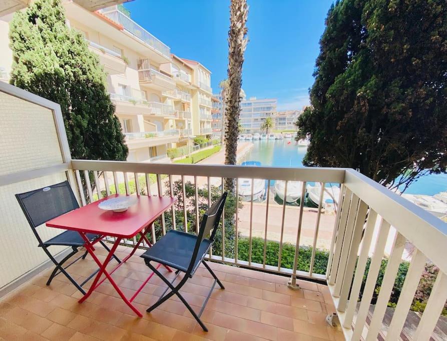 d'une table rouge et de deux chaises sur un balcon. dans l'établissement Appartement pour 4 vue sur la marina de Canet, à Canet