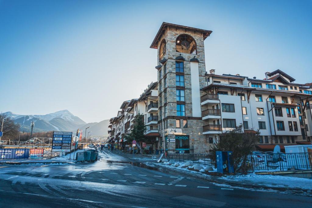 a building with a clock tower on the side of a street at IG Apartments Royal Towers 426 in Bansko
