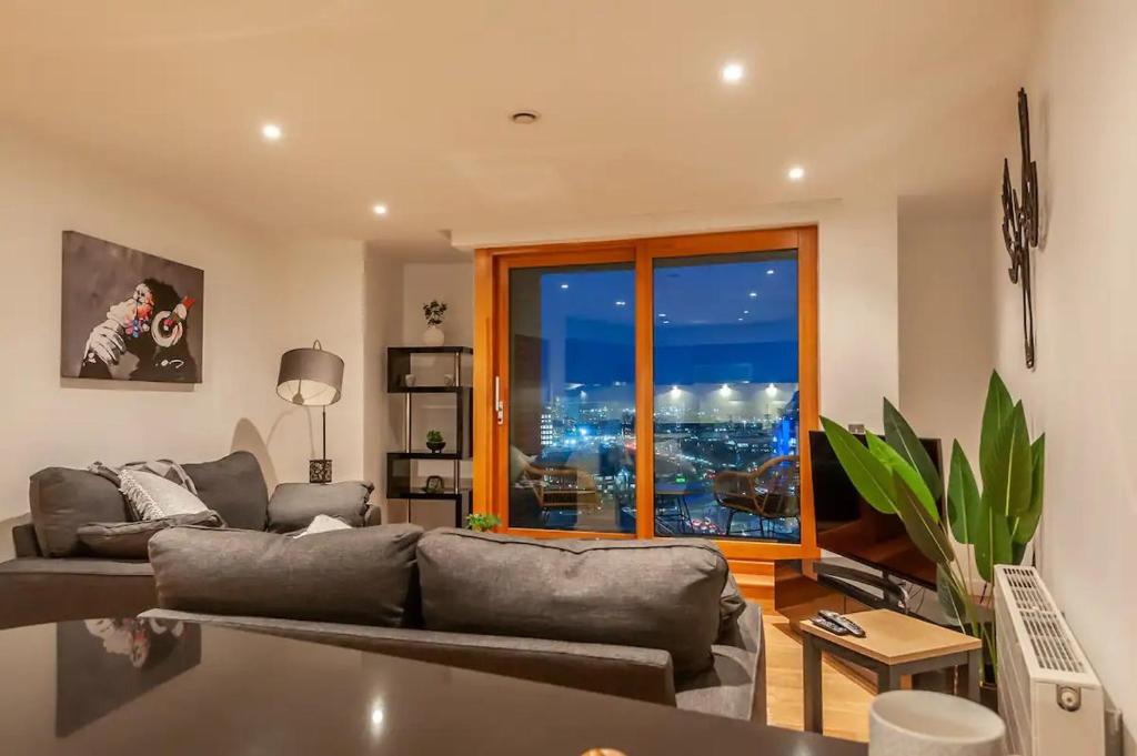 a living room with a couch and a large window at Pass the Keys Granary Wharf Deluxe - balcony and rooftop garden in Leeds