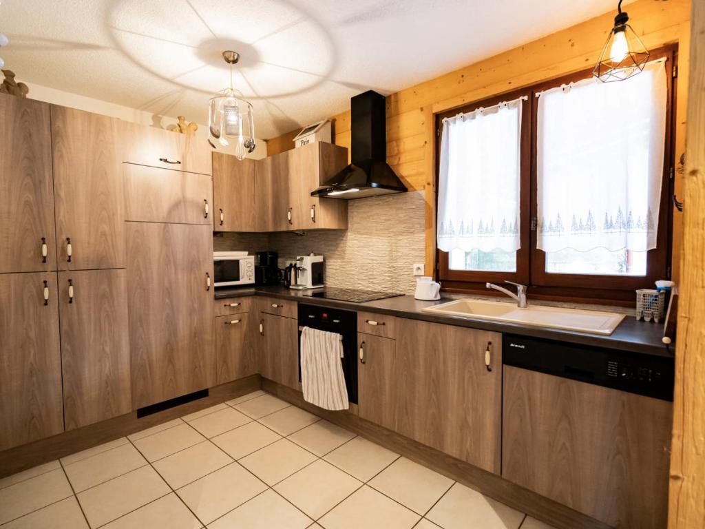 a kitchen with wooden cabinets and a sink and a window at Bel Appartement 3 Pièces avec Balcon, Proche Centre Châtel, Parking et Connexion WiFi - FR-1-676-119 in Châtel