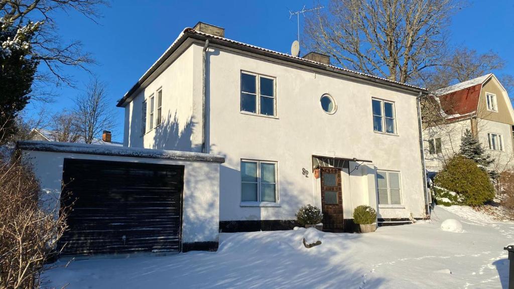 une maison blanche avec un garage dans la neige dans l'établissement Storgatan 82 Virserum, à Virserum