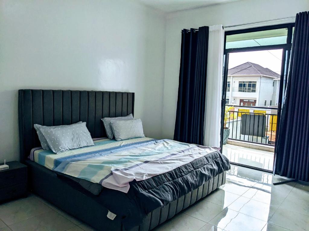 uma cama num quarto com uma grande janela em Homestay in Kigali, Rusororo em Masaka