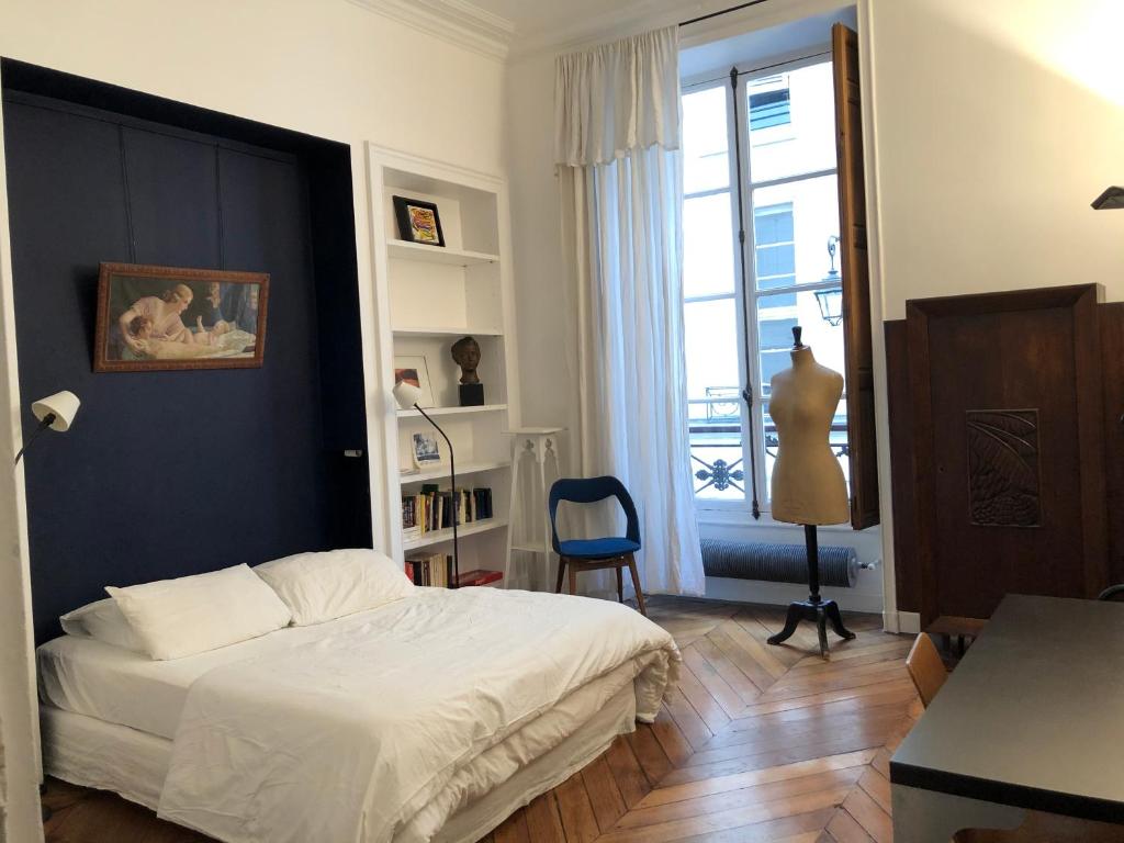 ein Schlafzimmer mit einem weißen Bett und einer blauen Wand in der Unterkunft Beautiful studio in the heart of Le Marais in Paris