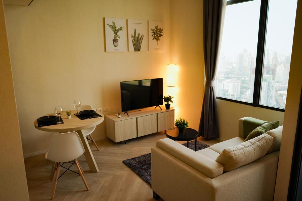 ein Wohnzimmer mit einem Sofa, einem TV und einem Tisch in der Unterkunft On Nut Duplex with City Views, 5-minute Walk to BTS, Ideal Long Stays in Bangkok
