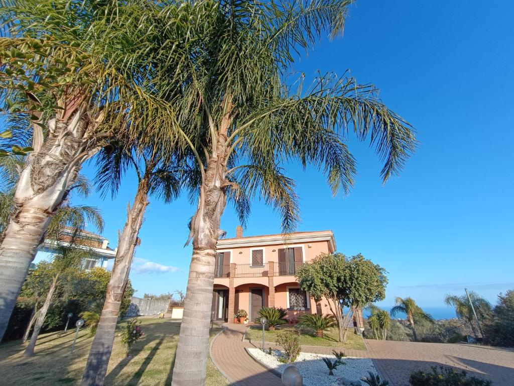 una casa con dos palmeras delante de ella en Villa Feluchia Tra Il Mare E Il Vulcano, en Acireale