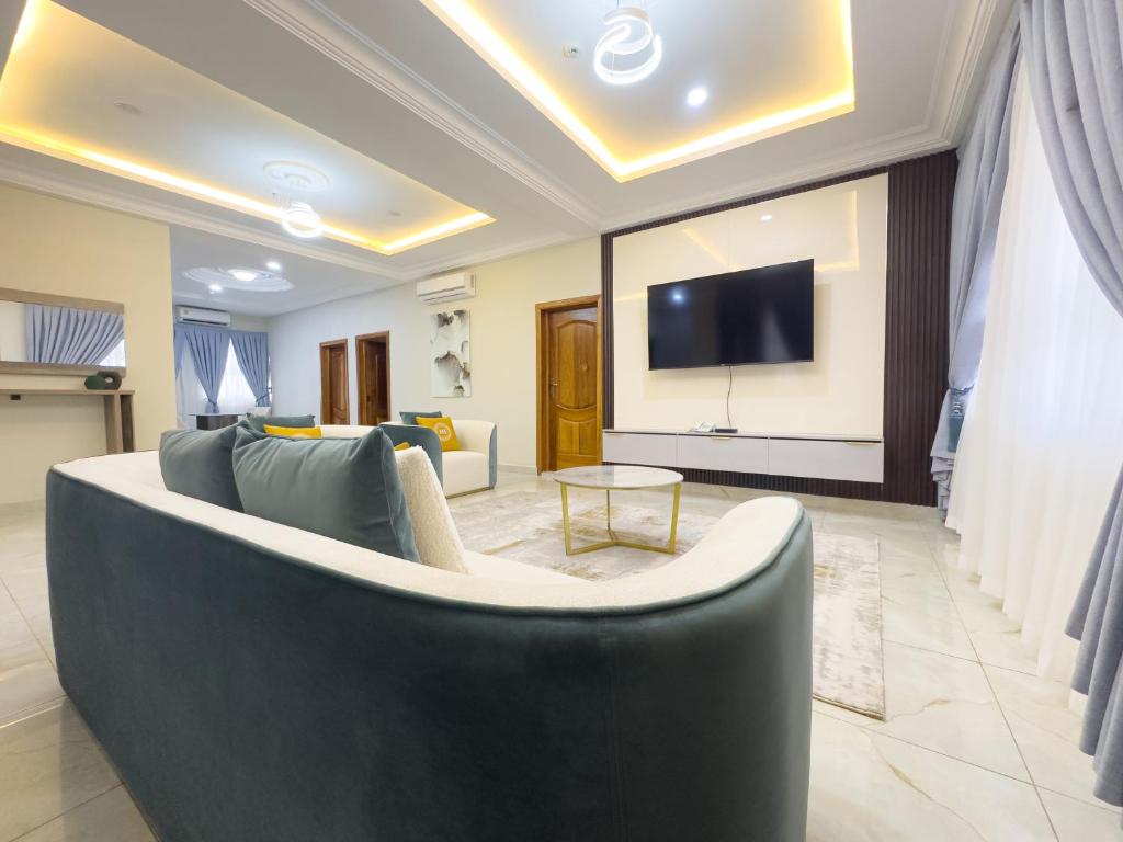 ein Wohnzimmer mit einem Sofa und einem Flachbild-TV in der Unterkunft The AUD Luxury Apartments in Kumasi