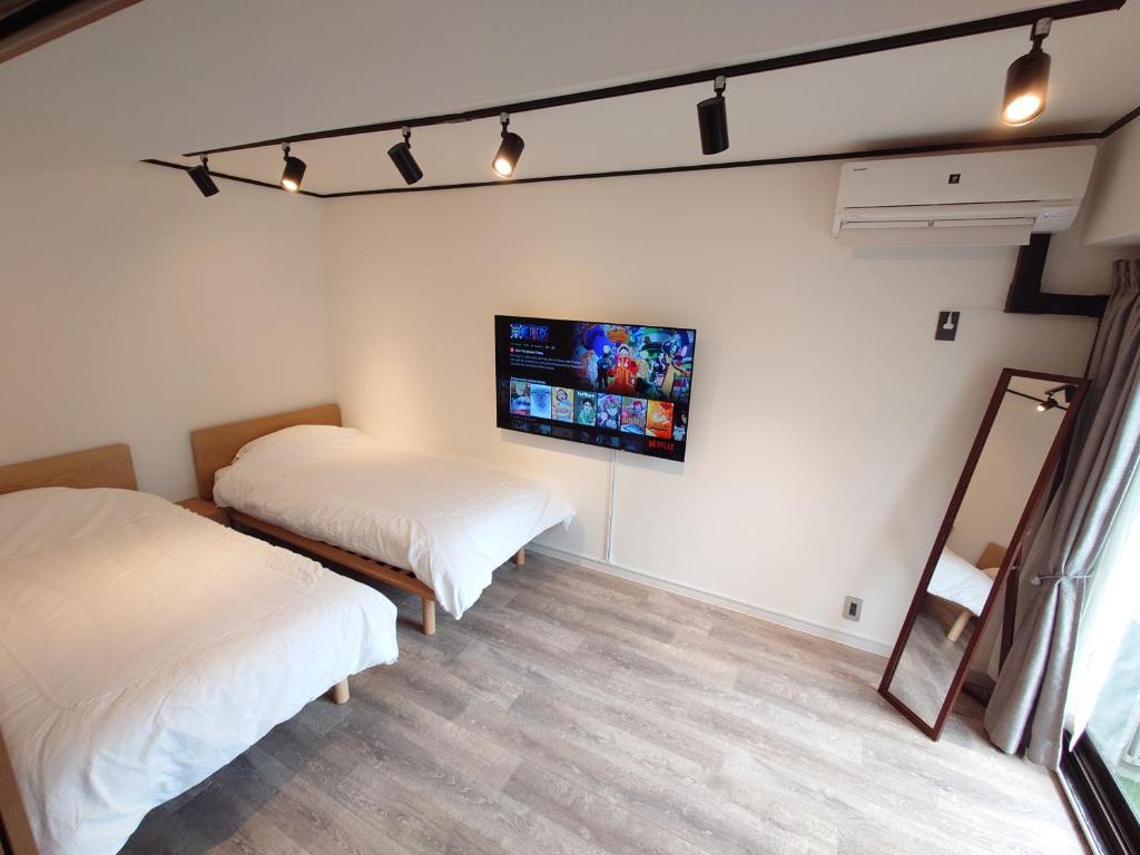 a bedroom with two beds and a tv on the wall at NIYS apartments 53 type in Tokyo