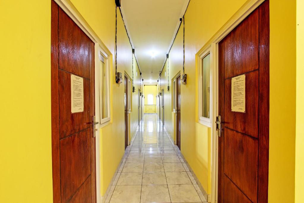un largo pasillo con paredes amarillas y puertas de madera en OYO 92792 Umi Rahayu Guesthouse, en Semarang