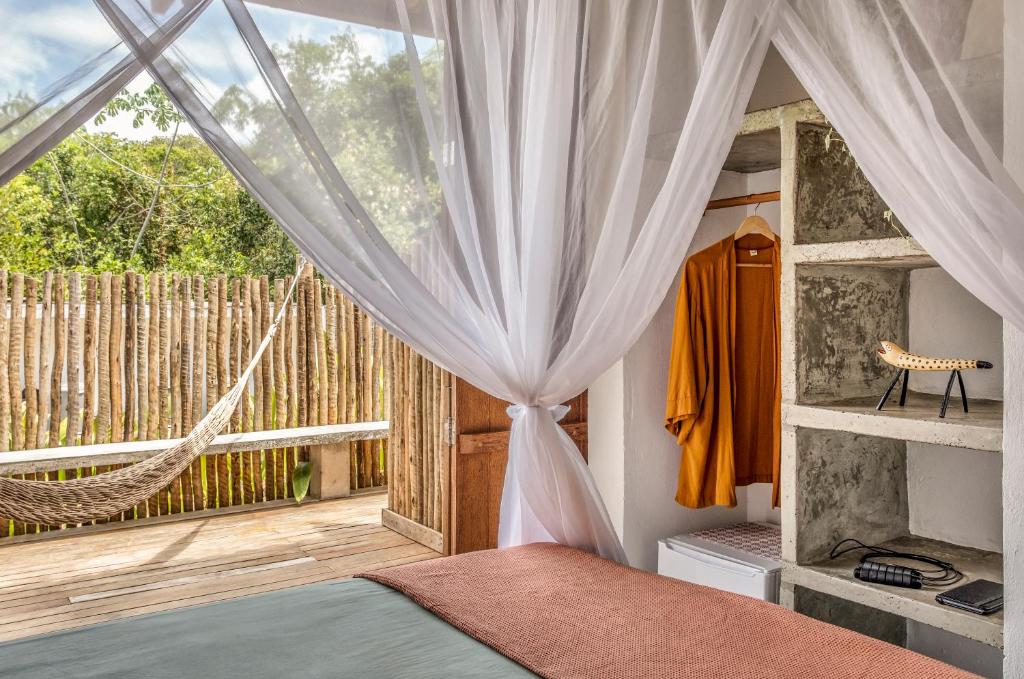 um quarto com uma rede de descanso e uma grande janela em Casa Canoa - Praia de Algodões em Maraú